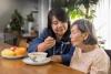 A female helper is feeding an aging woman at home